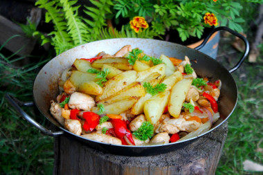 Курица с овощами в сковороде на костре